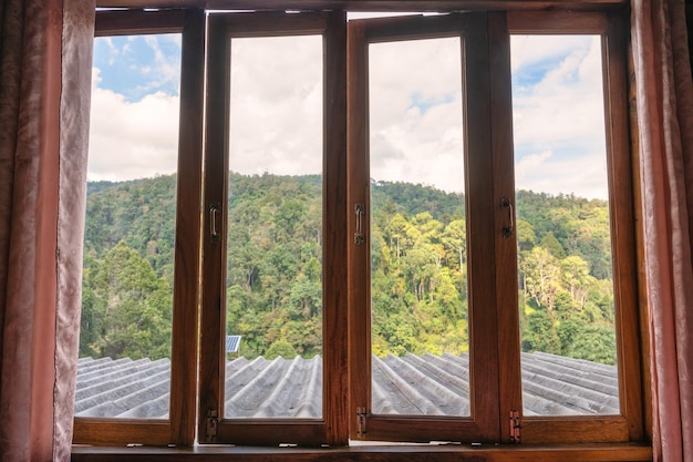 休暇中の熱帯雨林に囲まれた地元のホームステイのカーテン付きの木製窓