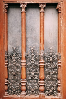 Una finestra in legno con un reticolo metallico con motivi fino al centro e colonne in legno
