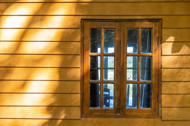 Деревянное окно на деревянной стене с солнечностью.