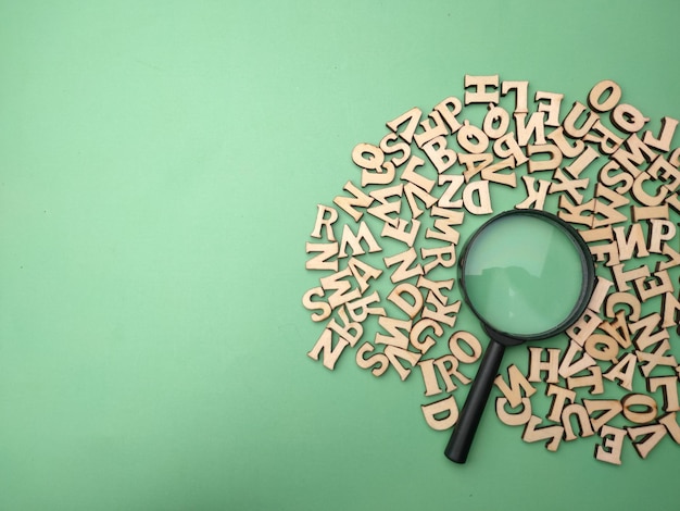 Photo wooden word and magnifying glass on a green background