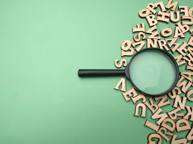 Photo wooden word and magnifying glass on a green background