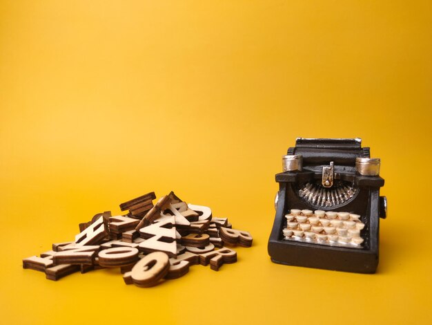 Wooden word and vintage black typewriter on the yellow background