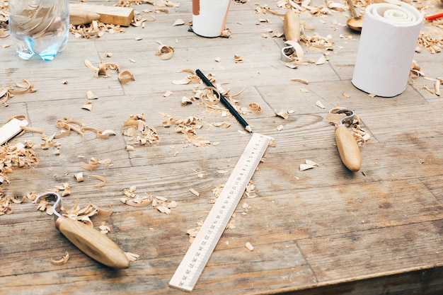 Wooden workshop Carving spoon from wood working with chisel Process of making wooden spoon chisel pencil compass ruler on dirty table with shavings Handmade festival
