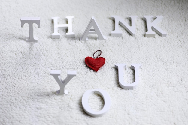 Photo wooden wthite letter thank you on the crumpled carpet on the floor