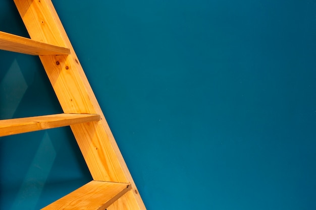 Wooden yellow ladder on blue wall background. colorfull interior abstract space for text