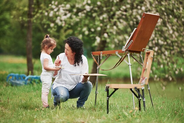 In woods. Teaching granddaughter how to paint. In the natural parkland