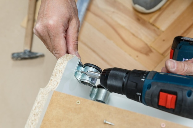 Woodwork repairman assembling a furniture using a drill