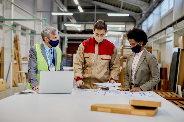 woodworking foreman and company managers going through design plans at production facility during coronavirus pandemic