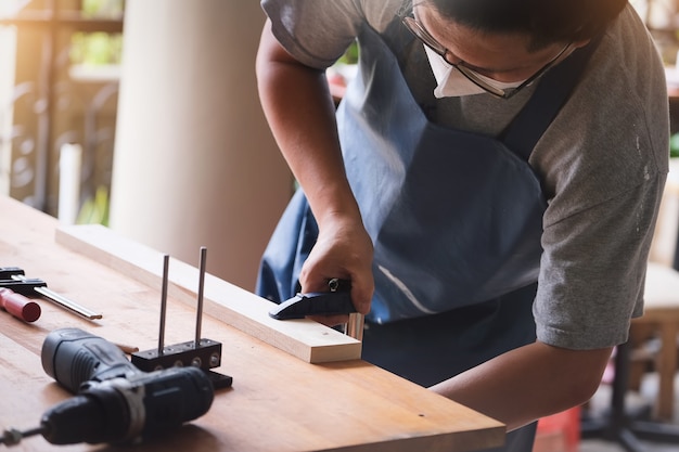 木工オペレーターは、顧客のために木製のテーブルを組み立てて構築するために木片を装飾しています