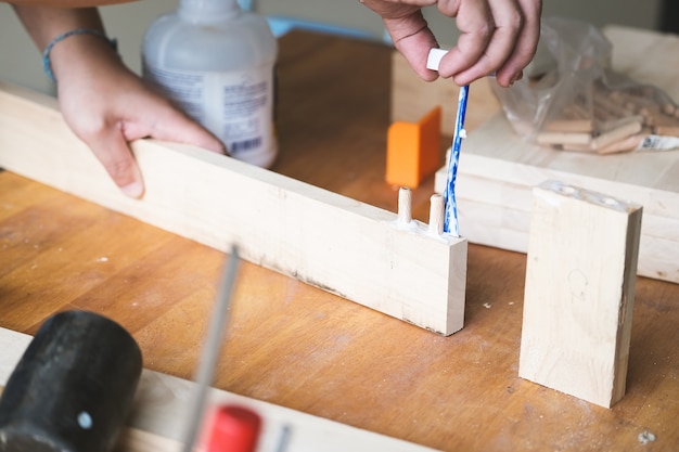 Фото Операторы деревообработки используют клей, чтобы собрать деревянные детали, чтобы собрать и построить деревянный стол для своих клиентов.
