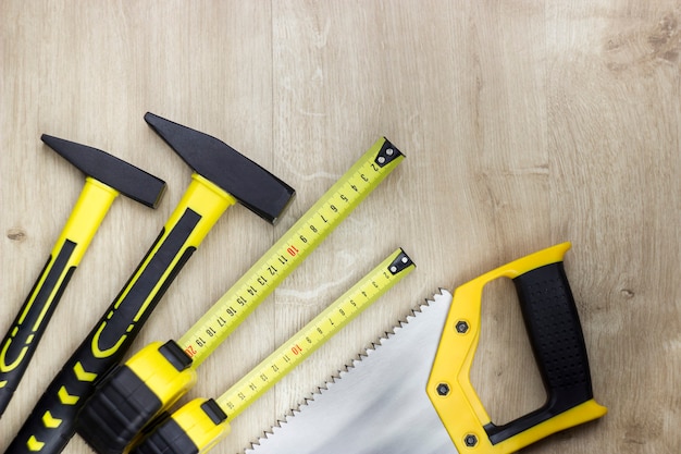 Woodworking tools on wood background. Hammer, steel tape measure and hand saw.