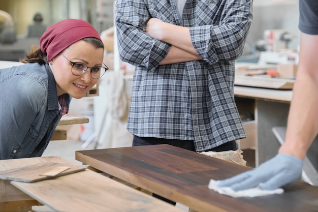 Officina di falegnameria, lavoratore che vernicia il primo piano di legno dello scaffale