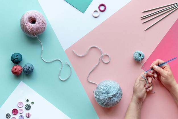 Filato di lana gomitoli di cotone e ferri da maglia hobby di lavoro a maglia creativo sfondo panoramico in rosa menta verde bianco disposizione hobby di colore pastello su sfondo rosa bianco menta a strati