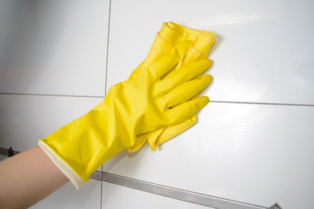 A wooman washer is cleaning tiled surface in kitchen The girl is holding a yellow rag in his hands Copy space