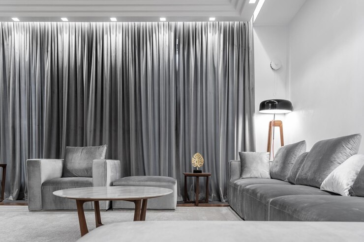 Foto woonkamer grijze bank fauteuil ronde tafel houten koffietafel tapijt lamp grijze gordijnen