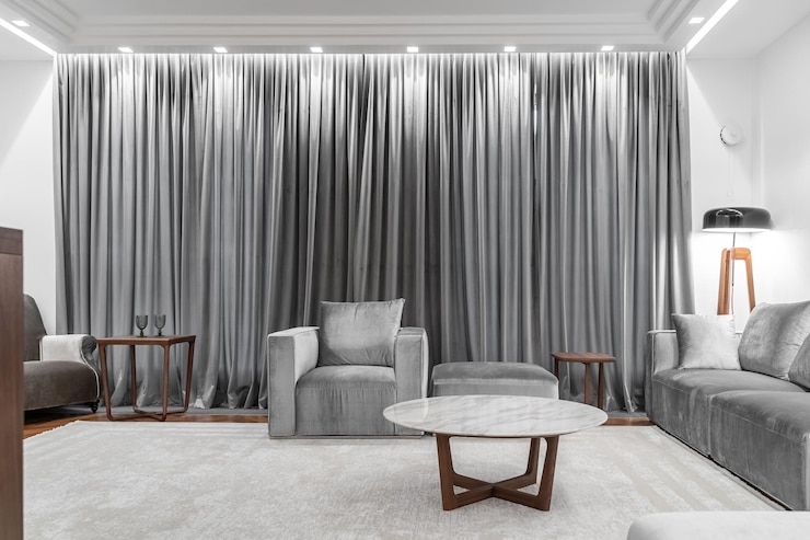 Foto woonkamer in witte grijze tonen grijze bank fauteuil koffietafel tapijt vloerlamp gordijnen