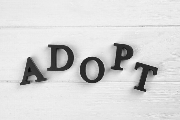 Foto woord adopt gemaakt van letters op een houten achtergrond kinderopvangconcept