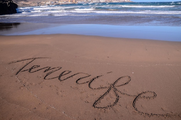 Woord geschreven op het zand van een tropisch strand