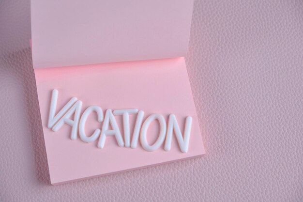 Woord vakantie opgemaakt met witte letters roze stuk papier Concept vakantie rust en reizen