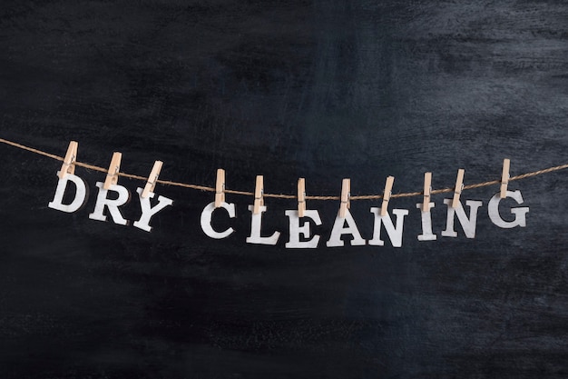 Woorden DRY CLEANING hangt aan wasknijpers tegen zwarte ondergrond. Concept van wasservice.