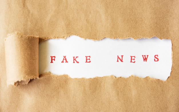 Woorden fake news geschreven onder gescheurd papier