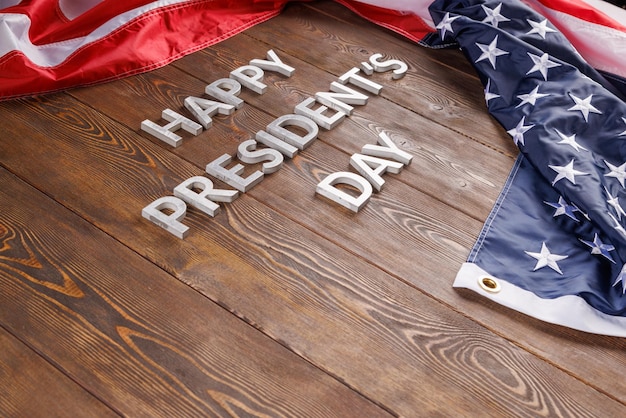 Foto woorden gelukkige presidentendag gelegd met echte letters op een houten bord in de buurt van de amerikaanse vlag