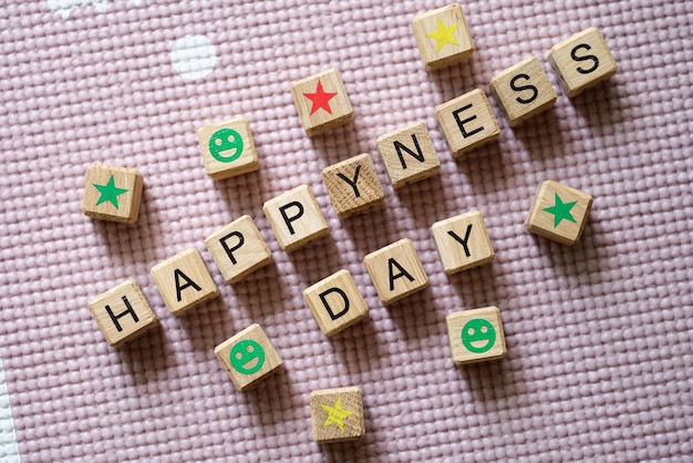 Woorden geluksdag is geschreven in houten kubussen tussen sterren en glimlacht close-up goed humeur