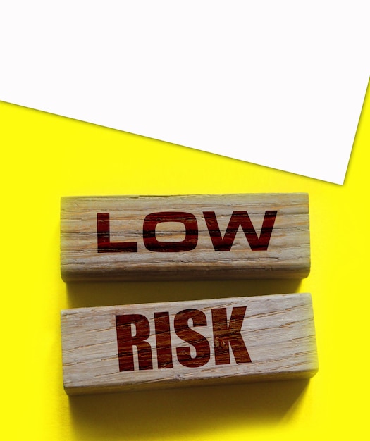 Woorden houten blokken met een laag risico op geel Bedrijfsinvesteringsrisico's concept