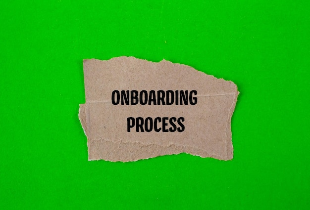 Woorden van het onboardingproces geschreven op een gescheurd stuk papier met een groene achtergrond Conceptueel symbool