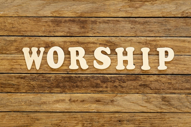 Word aanbidding geschreven met houten letters op houten achtergrond bovenaanzicht
