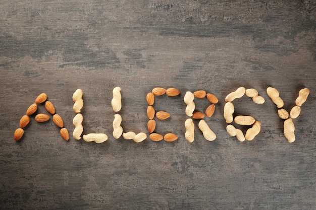 Word ALLERGY made of nuts on color background