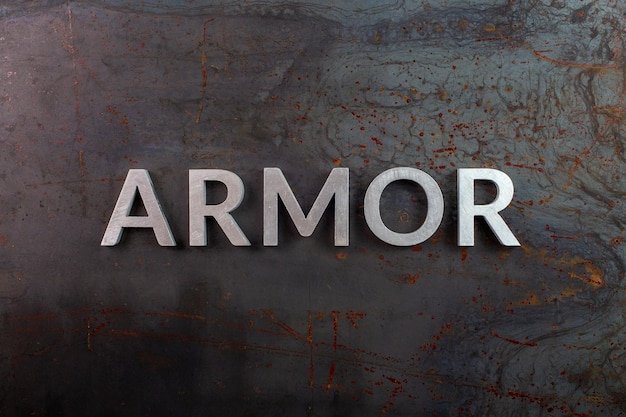 Photo the word armor laid with silver metal letters on rusted black iron flat surface background in flat lay composition