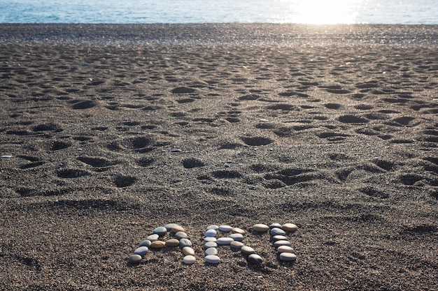 Word art gemaakt van stenen op zandstrand