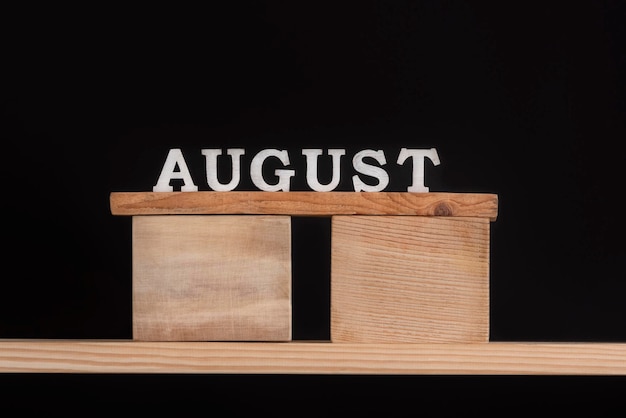 Word August made of wooden letters on black background Front view Summer calendar