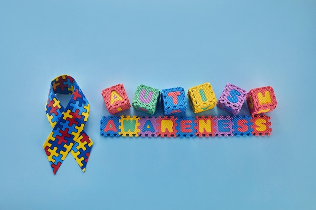 Word autisme bewustzijnsdag autisme bewustzijnslint en puzzelkubussen op blauwe achtergrond