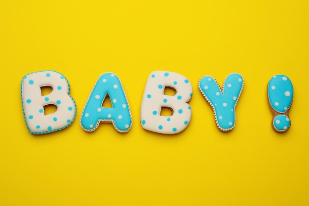 Word BABY made of tasty cookies on yellow background flat lay