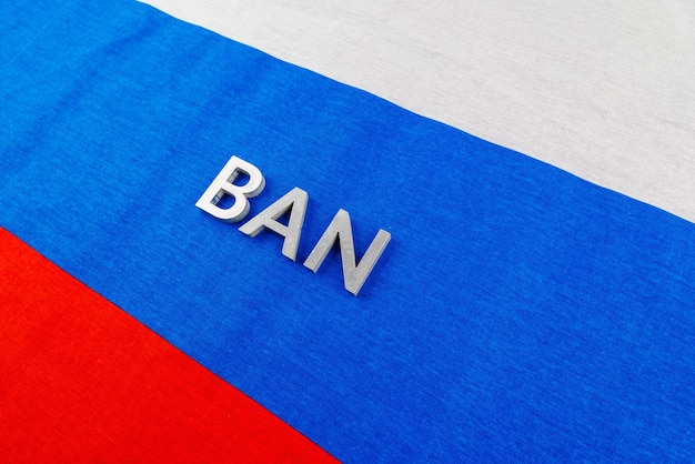 The word ban laid with silver metal letters over fabric tricolor flag of the Russian Federation