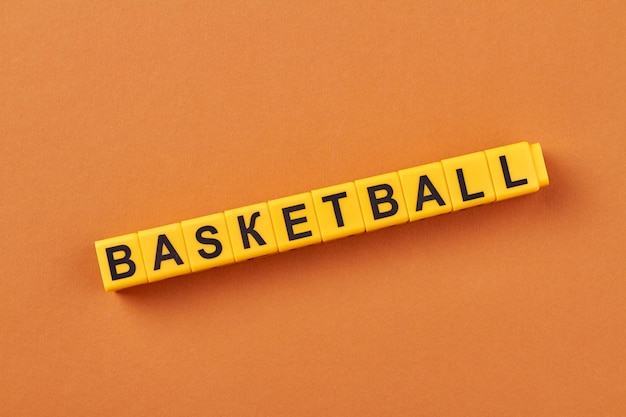 The word basketball written on yellow cubes against color background flat lay minimal