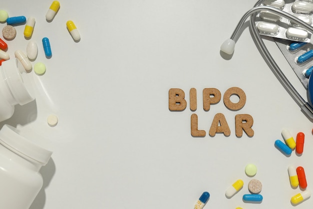 The word bipolar on the background of a stethoscope and pills place for text