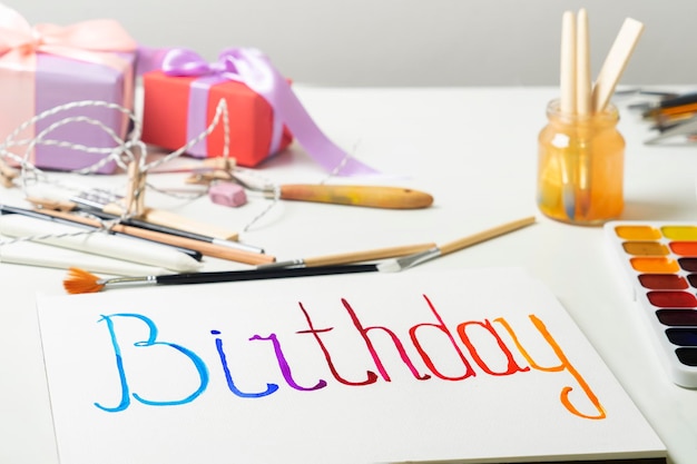 Фото Слово день рождения нарисовано на листе бумаги акварельными красками готовимся к празднику своими руками