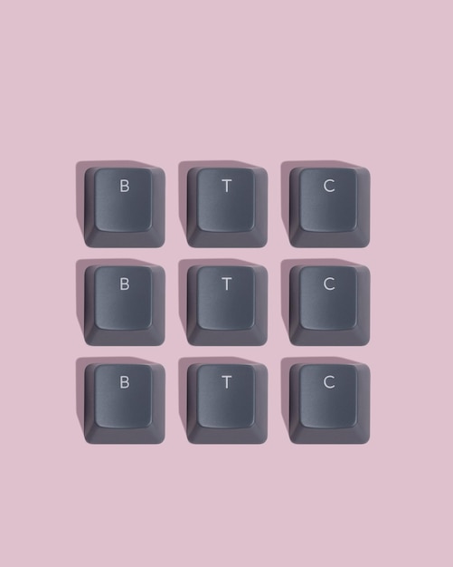 Photo the word btc is laid out from gray keyboard keycaps on pink background pattern
