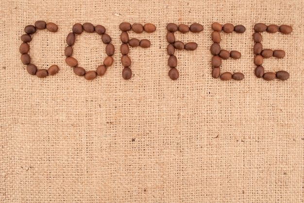 The word coffee made from coffee beans on burlap background