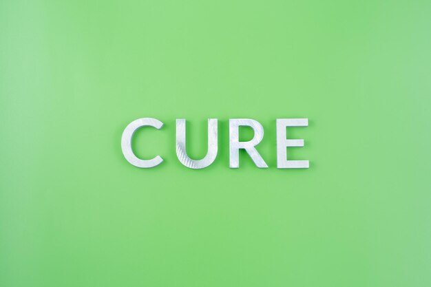 The word cure laid with thick aluminium letters on green background