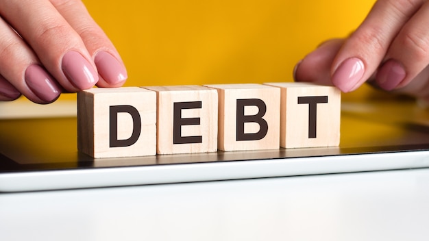 The word debt written on wooden cubes standing on a notepad. selective focus. business, financial concept