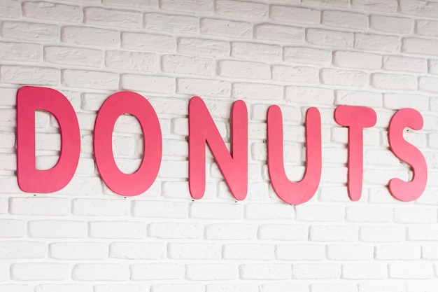 The word donuts on a white wall in a cafe interior decor in a cafe with donuts closeup lettering