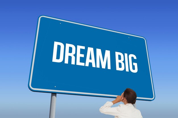 The word dream big and thinking businesswoman against bright blue sky