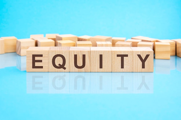 Word equity made with wood building blocks blue background business concept