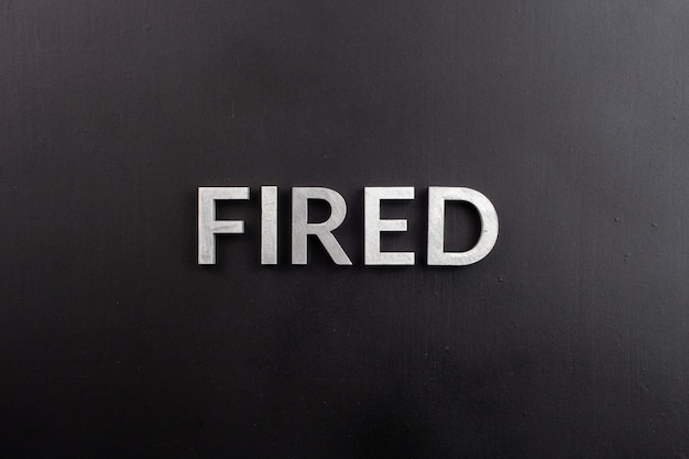 The word fired laid with white brushed metal letters on flat black surface