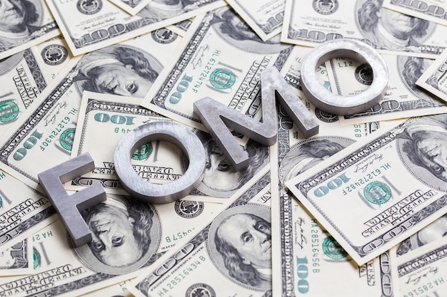 The word FOMO laid with aluminium letters on the US dollar banknotes background with selective focus