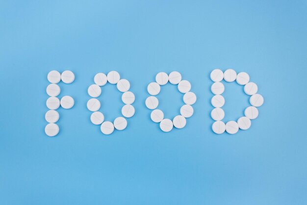 The word food made from medical pills on a blue background. Drug addiction and overdose concept.